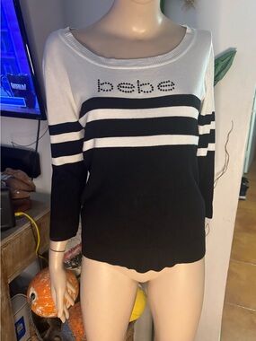BEBE top round neck, 3/4 sleeves. Black & white stripes. Logo embellished Great